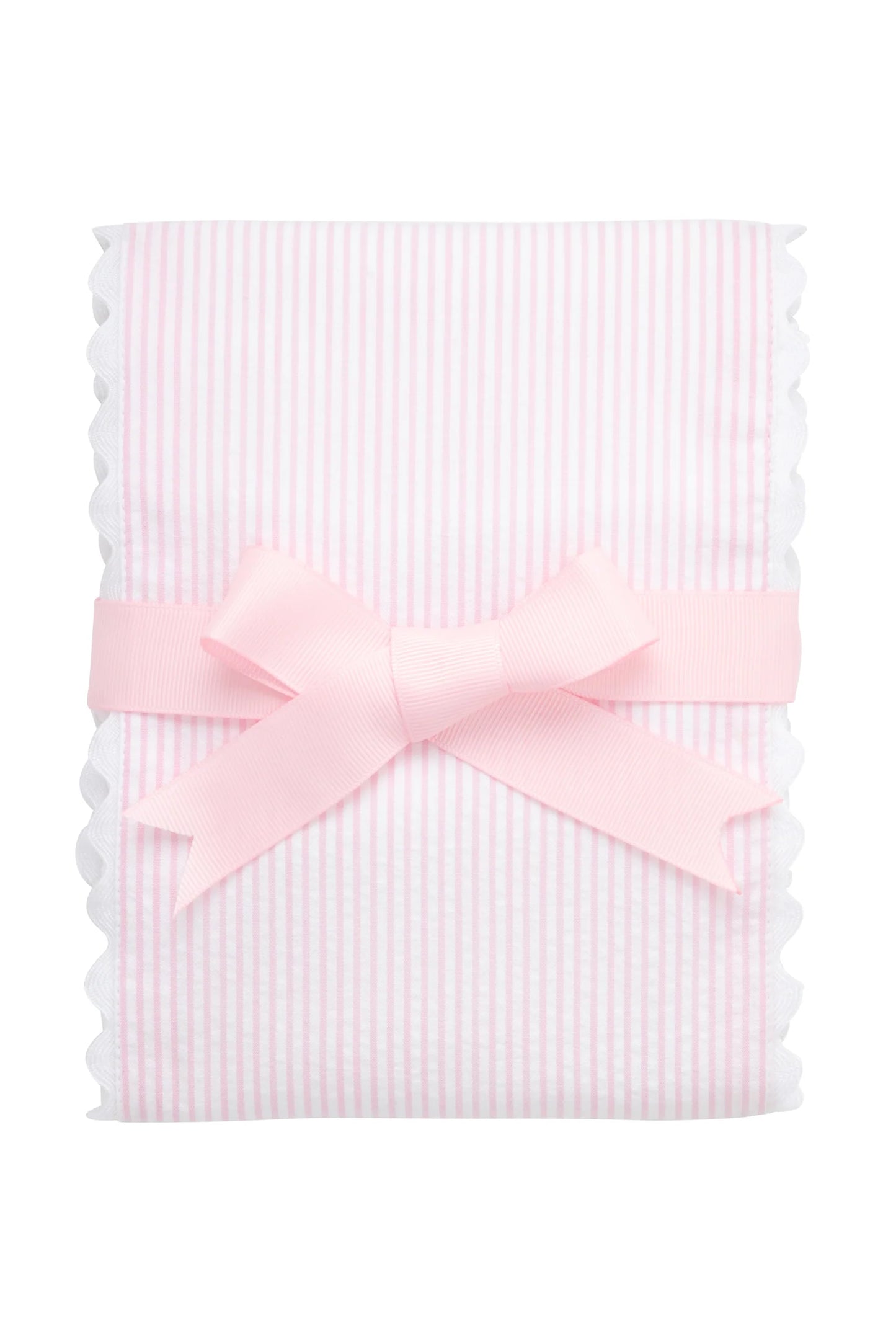 White burp cloth trimmed in light-pink seersucker stripe with ric rac edge, folded and tied with a white bow against a white background.