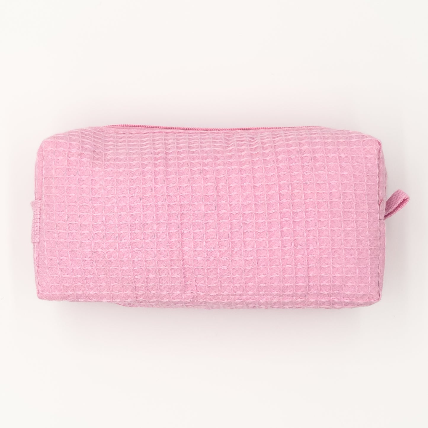 Small rectangular cosmetic bag in light-pink waffle-weave fabric with a top zipper; compact travel size. Textured surface ready for personalization.