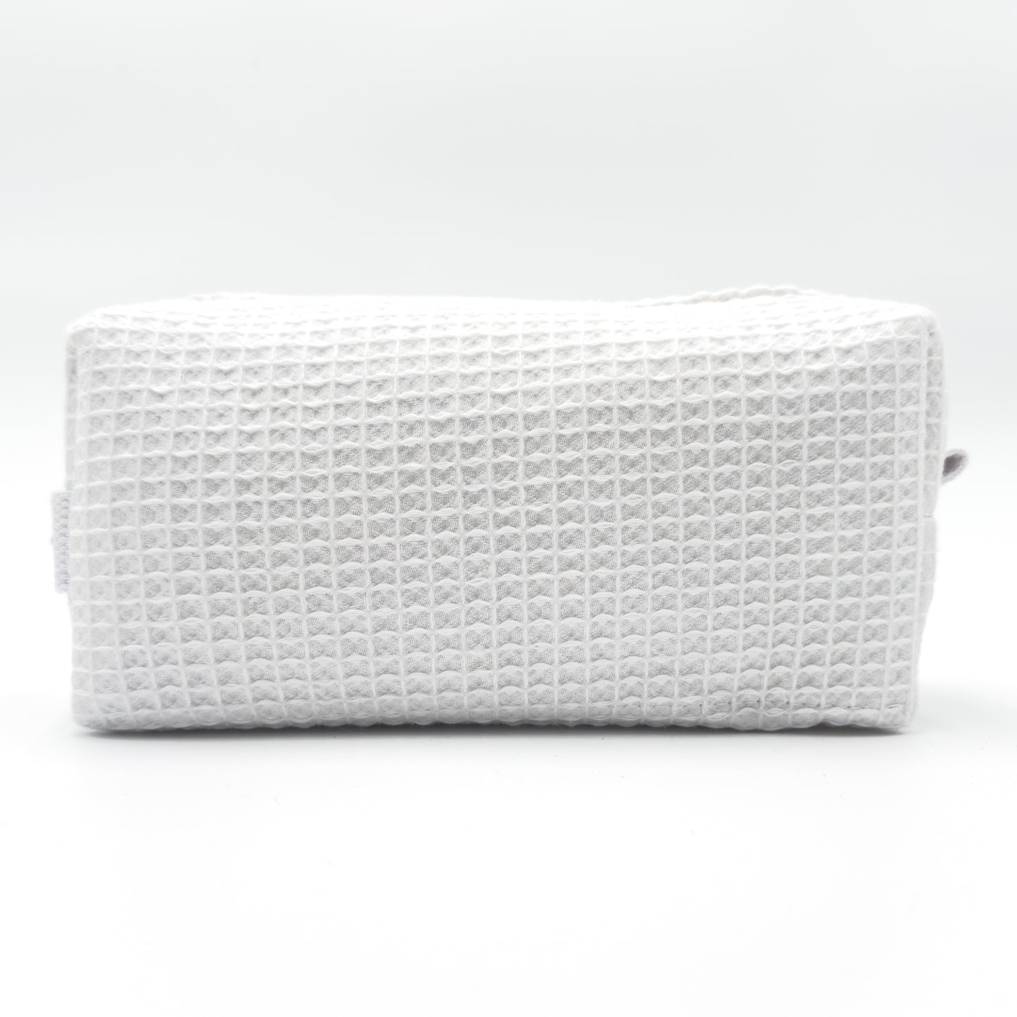Small rectangular cosmetic bag in white waffle-weave fabric with a top zipper; compact travel size. Textured surface ready for personalization.