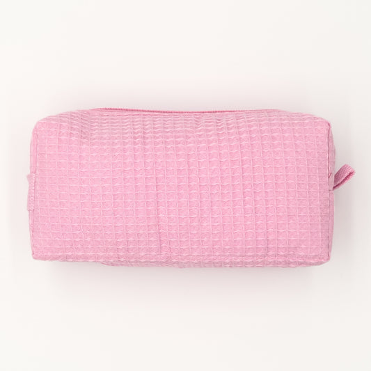 Small rectangular cosmetic bag in light-pink waffle-weave fabric with a top zipper; compact travel size. Textured surface ready for personalization.